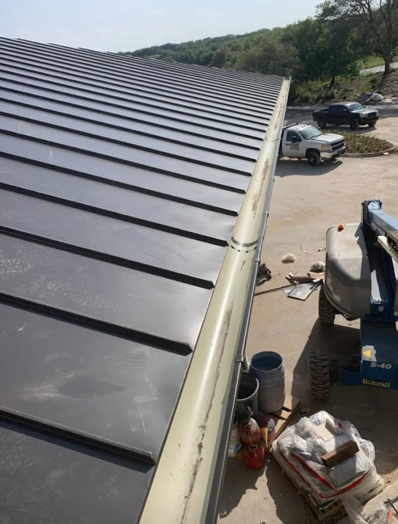 Standing seam panel and gutter detail on a metal roofing jobsite in Exeter